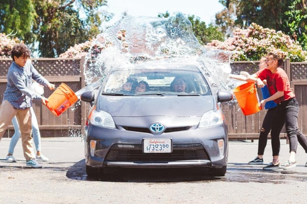 Volunteers splashing a car with water